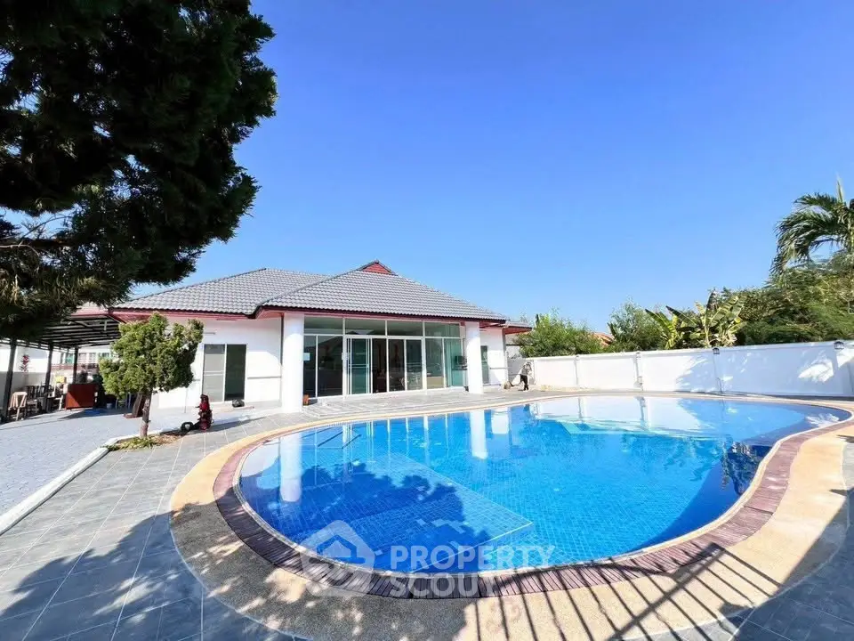 Luxurious villa with stunning pool and spacious outdoor area under clear blue sky.