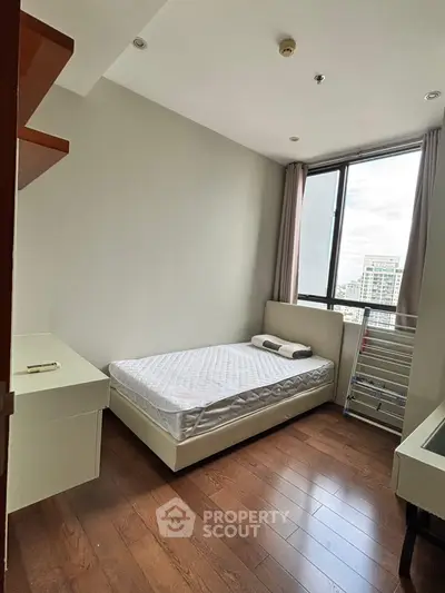 Modern bedroom with large window and wooden flooring in urban apartment