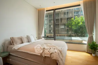 Luxurious bedroom with large window offering stunning city view, elegant decor, and natural light.