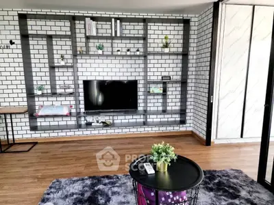 Modern living room with stylish brick wall and built-in shelving, featuring a sleek TV setup and cozy decor.