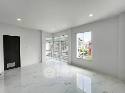 Spacious modern living room with large windows and balcony access, featuring sleek white tile flooring.