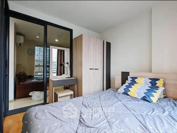 Cozy bedroom with modern decor and ample natural light in urban apartment.