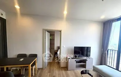 Modern living room with TV, dining area, and balcony view in a stylish apartment.