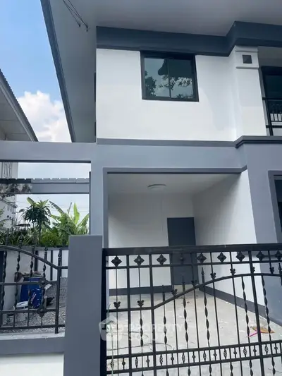Modern two-story house with sleek design and gated driveway, perfect for family living.