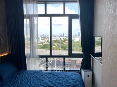 Modern bedroom with large window offering stunning cityscape view, featuring cozy blue bedding and elegant curtains.