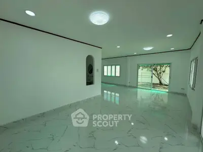Spacious modern living room with marble flooring and large windows offering natural light.