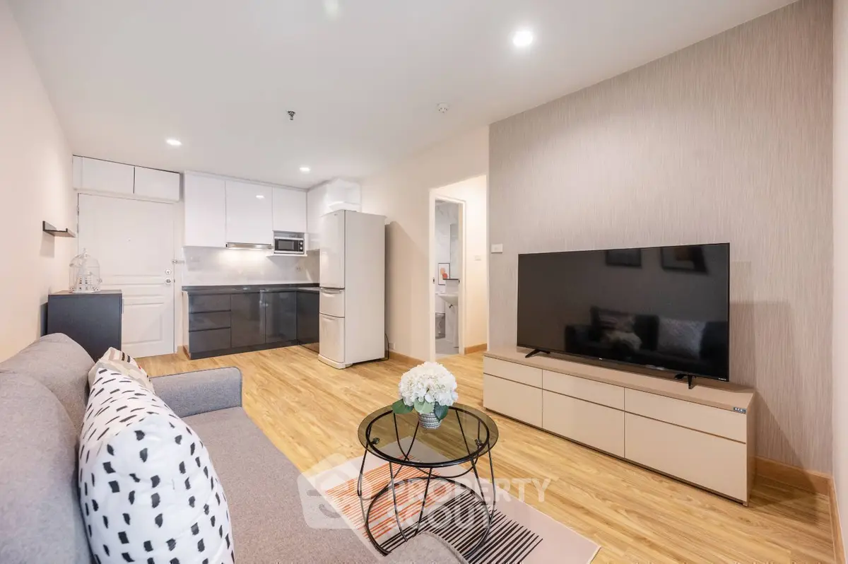 Modern living room with sleek design, featuring a large TV, stylish sofa, and contemporary kitchen area.