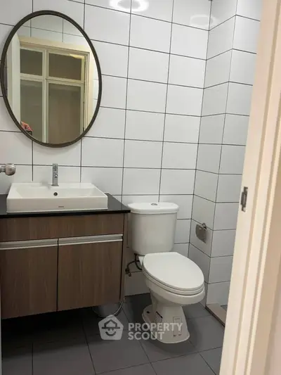 Modern bathroom with sleek vanity and round mirror in a contemporary apartment.