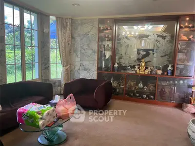 Elegant living room with large windows and decorative display cabinet.