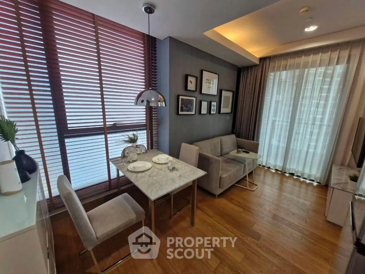 Modern living room with dining area, featuring stylish decor and natural light through large windows.