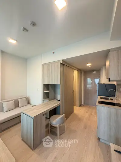 Modern studio apartment with sleek wooden furniture and compact kitchen area.