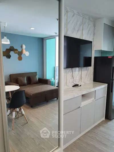 Modern living room with stylish decor and open kitchen layout, featuring a cozy sofa and sleek appliances.