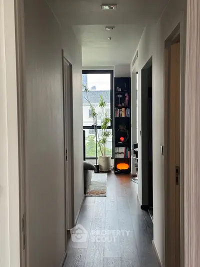 Modern apartment hallway leading to a cozy living area with natural light and stylish decor.