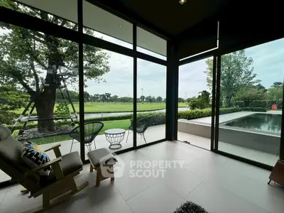 Luxurious living room with floor-to-ceiling windows overlooking a serene garden and pool area.