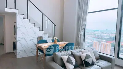 Modern living room with large windows and city view, featuring stylish furniture and elegant decor.