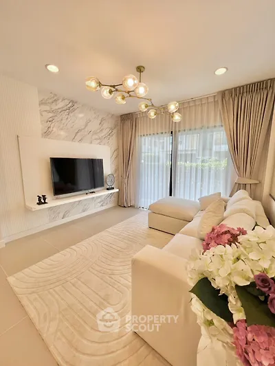Luxurious living room with elegant decor and modern lighting, featuring a plush white sofa and large TV.