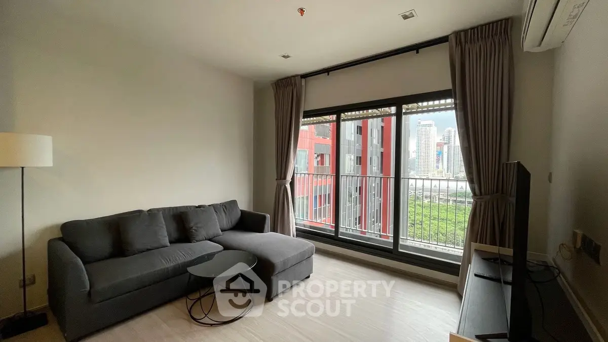 Modern living room with city view, featuring a cozy sofa and floor-to-ceiling windows.