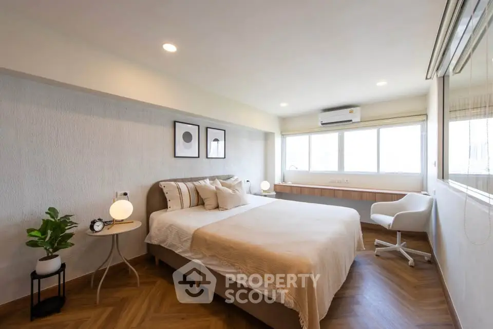 Spacious modern bedroom with elegant decor and large windows for natural light.