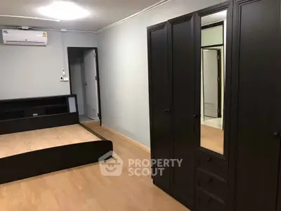 Spacious bedroom with modern dark wood furniture and air conditioning.