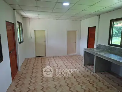 Spacious room with tiled flooring and multiple doors, ideal for versatile use.
