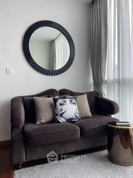 Stylish living room with plush sofa, decorative mirror, and elegant curtains.
