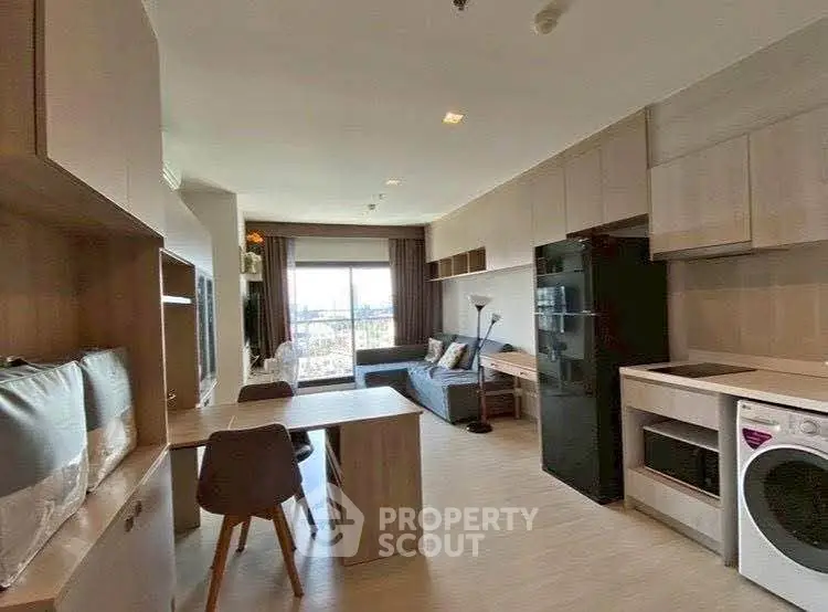 Modern open-layout living room with kitchen, featuring sleek furniture and large window view.
