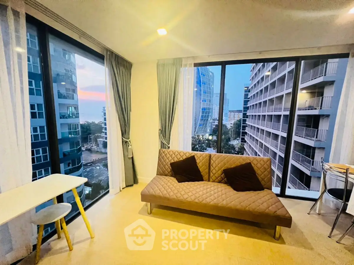 Modern living room with large windows and city view in a high-rise apartment.