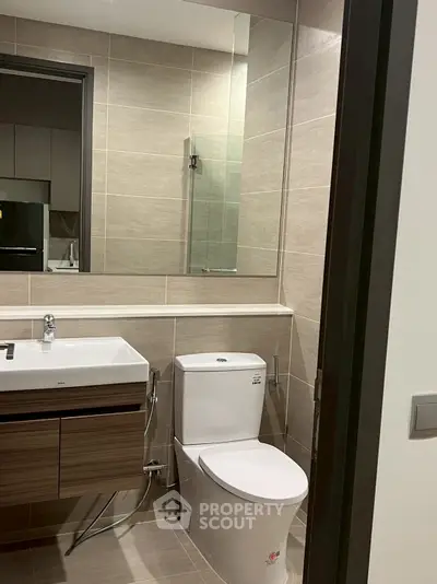 Modern bathroom with sleek fixtures and neutral tiles, featuring a stylish vanity and spacious mirror.