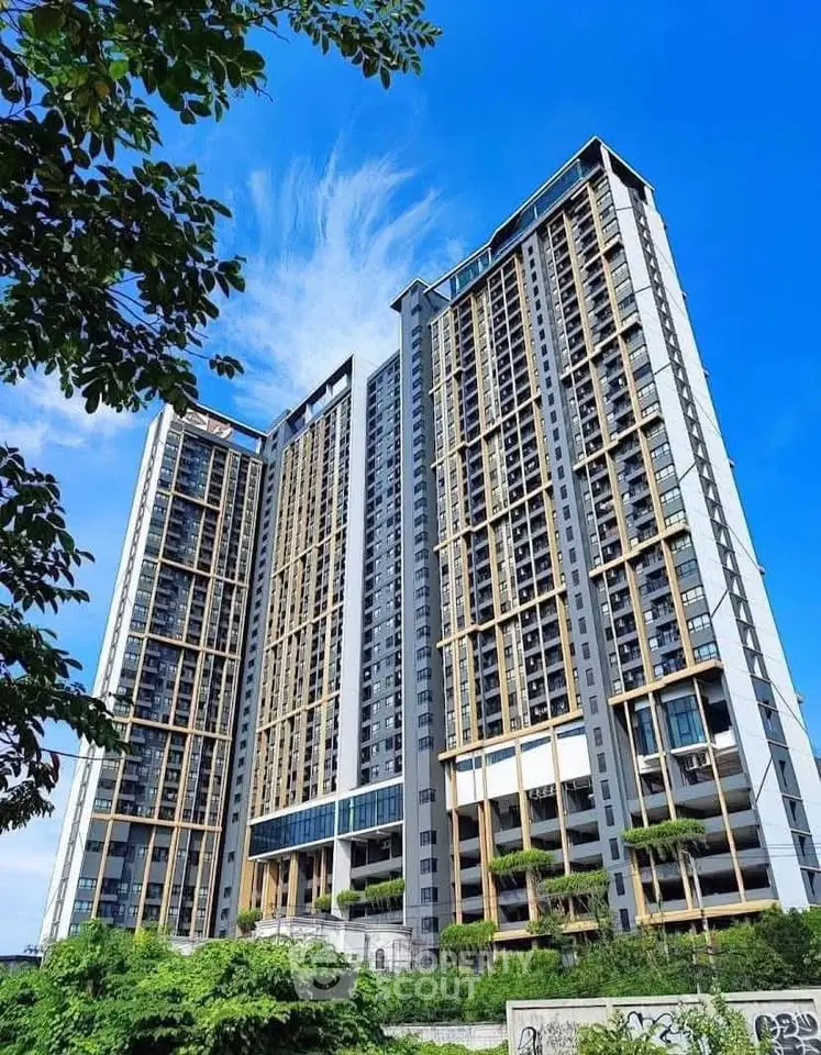 Stunning modern high-rise building with lush greenery and clear blue sky.