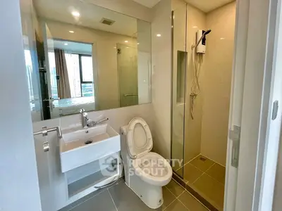 Modern bathroom with glass shower and sleek fixtures in contemporary apartment.