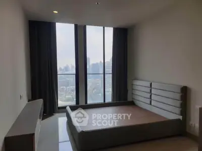 Spacious bedroom with large windows offering stunning city views in a modern apartment.