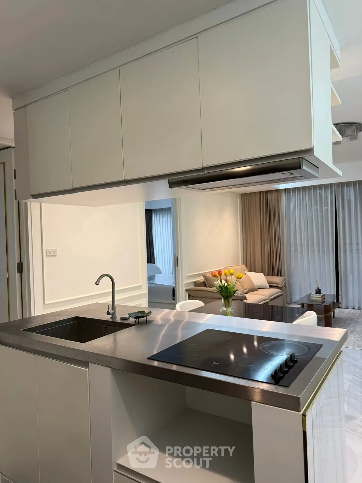 Modern kitchen with sleek design and open layout overlooking cozy living room.