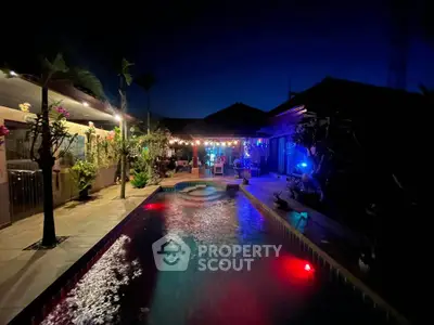 Luxurious night view of a private pool with ambient lighting and lush garden surroundings.