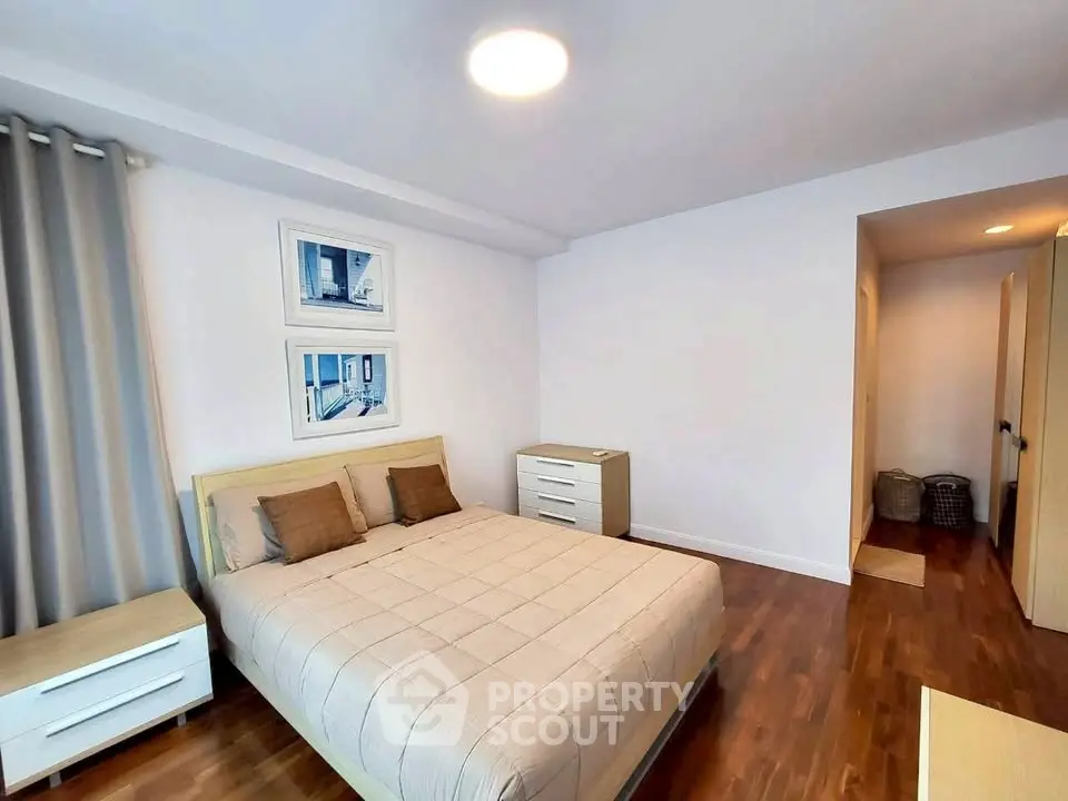 Spacious bedroom with modern decor and wooden flooring in a stylish apartment.