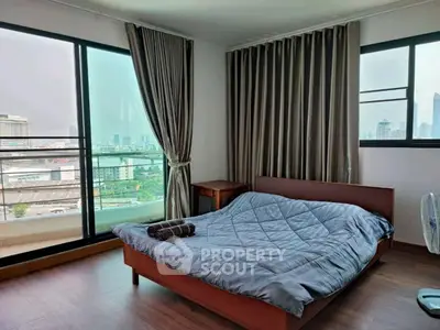 Spacious bedroom with city view and large windows, featuring modern decor and cozy ambiance.