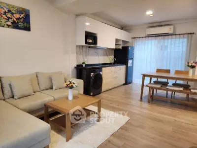 Modern open-plan living room with kitchen, featuring stylish furniture and natural light.