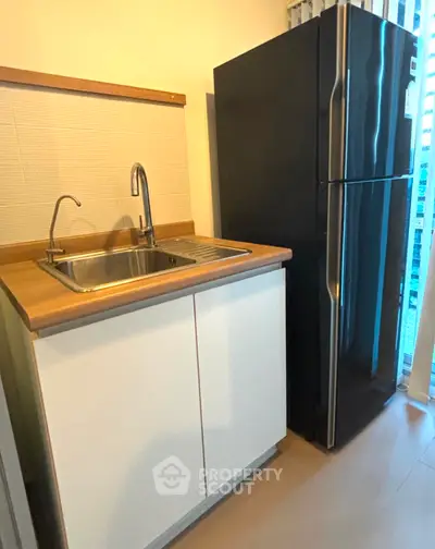 Compact kitchen with sleek black fridge and modern sink