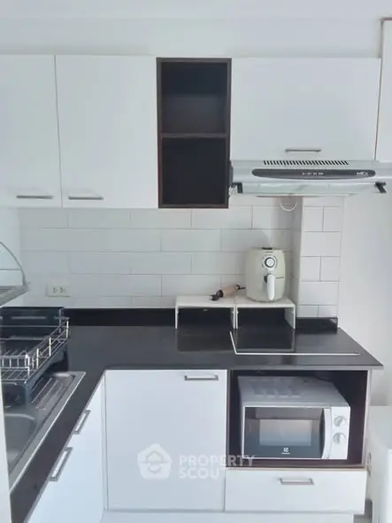 Modern kitchen with sleek white cabinets and built-in microwave oven.