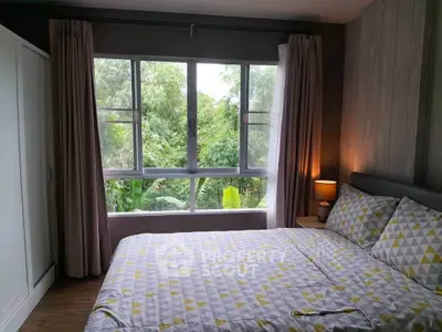 Cozy bedroom with large window and nature view, featuring modern decor and ample natural light.