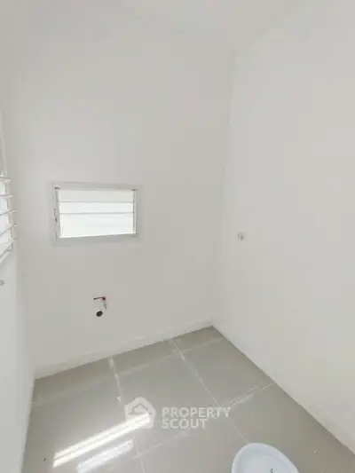 Minimalist white storage room with small window and tiled floor