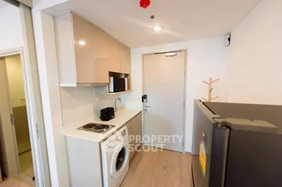 Modern compact kitchen with washing machine and sleek appliances in a cozy apartment.