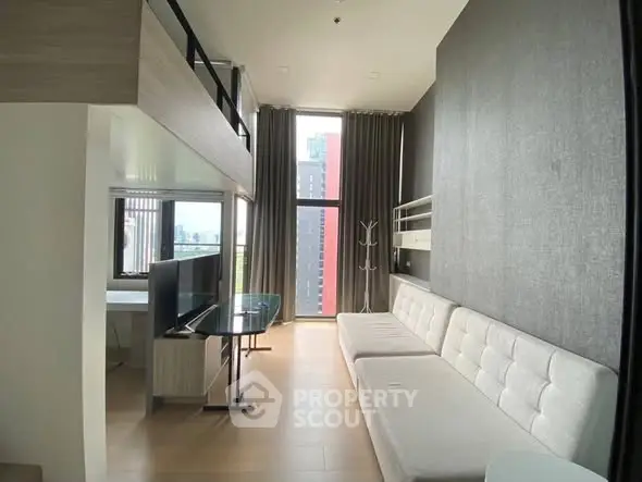 Modern loft-style living room with high ceilings and large windows offering city views.