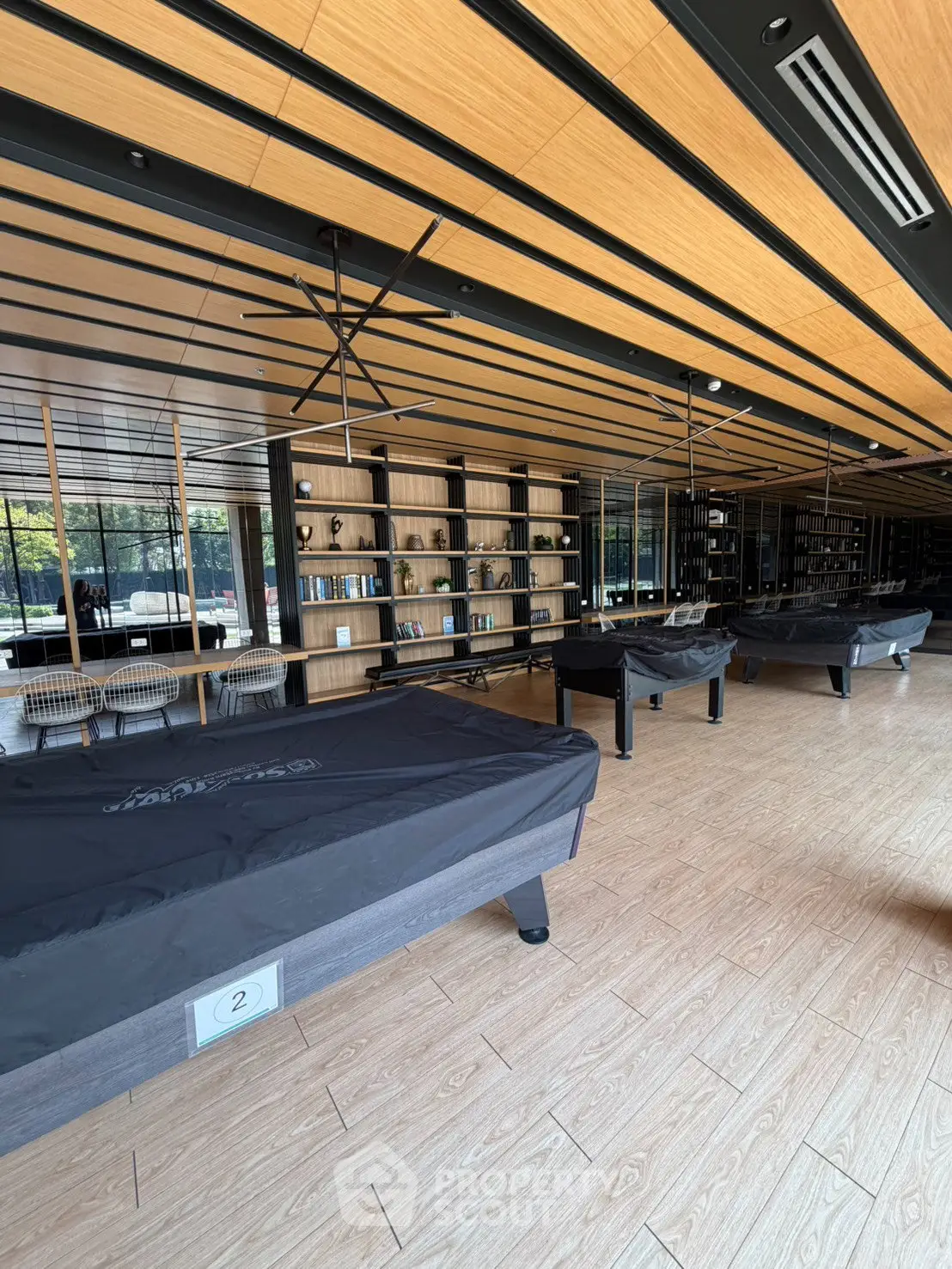 Spacious modern library with pool tables and wooden ceiling in luxury building