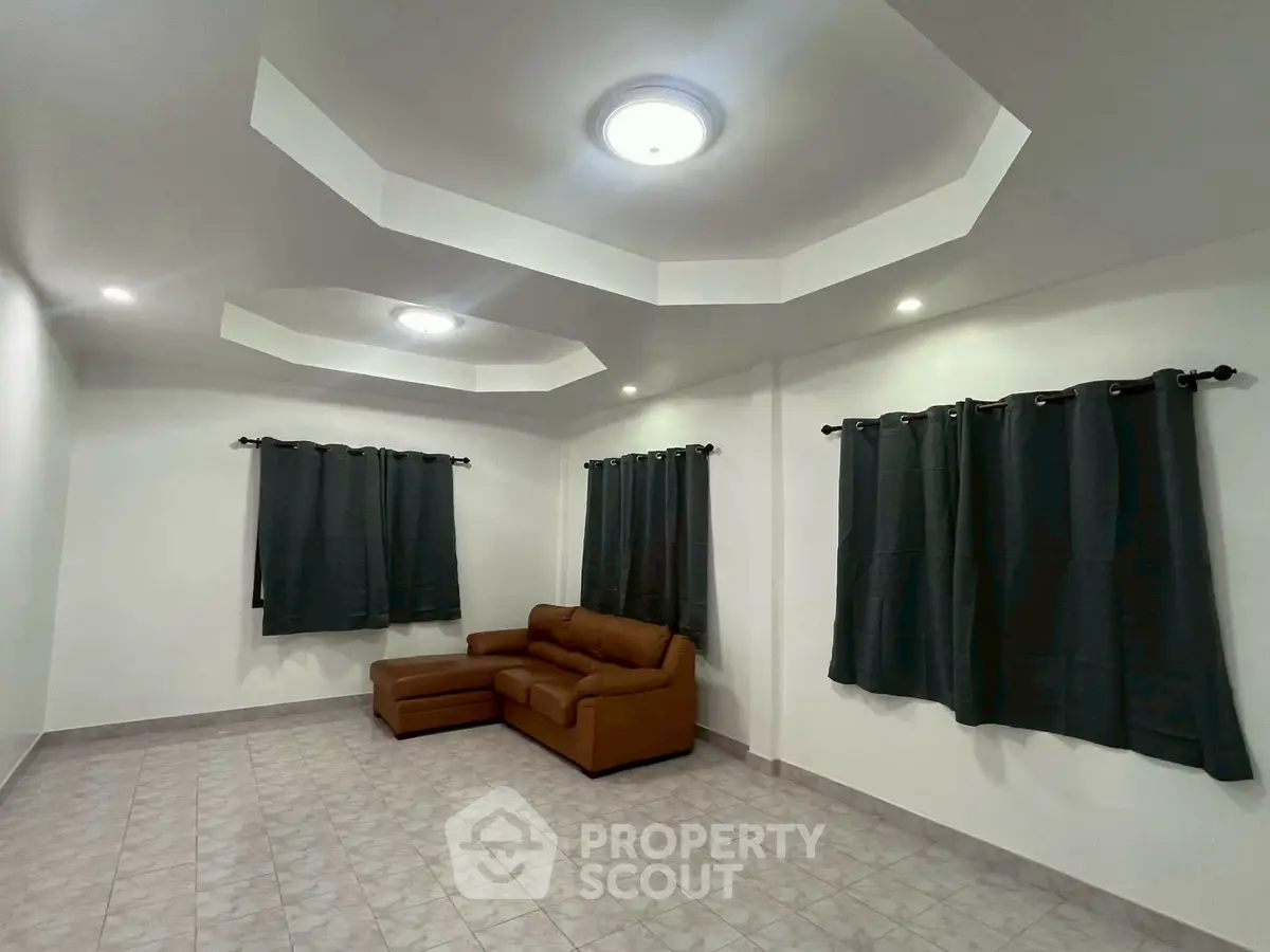 Spacious living room with modern ceiling design and cozy brown sofa, perfect for relaxation.
