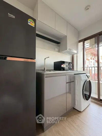 Modern kitchen with appliances including fridge and washing machine, bright natural light