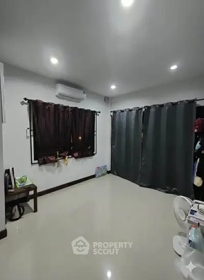 Spacious living room with modern lighting and sleek curtains, perfect for cozy gatherings.