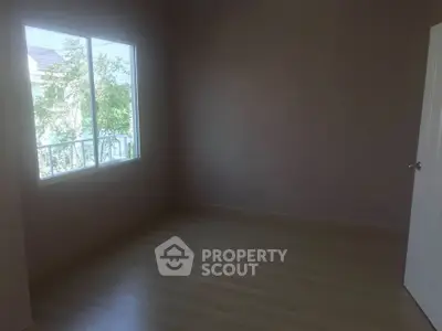 Spacious empty room with large window and wooden flooring, perfect for customization.