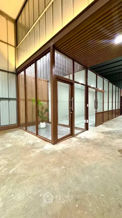 Modern industrial-style glass office space with high ceilings and sleek design.