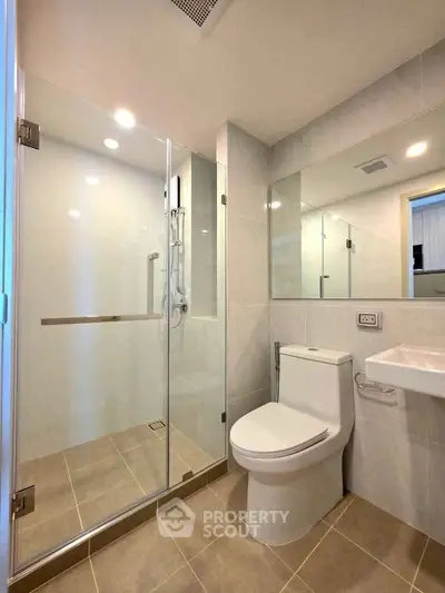 Modern bathroom with glass shower and sleek fixtures in a contemporary apartment.