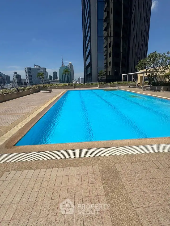 Luxurious rooftop pool with stunning city skyline views in modern high-rise building.
